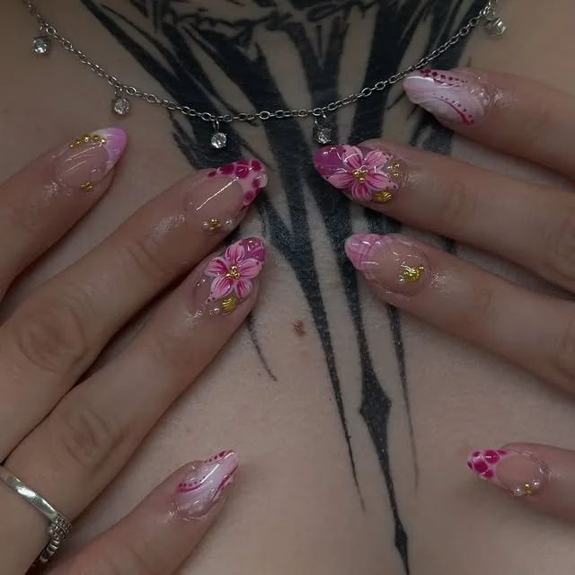 Rosa Gelnägel mit gemalten Blüten und Goldakzenten