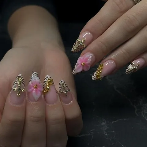 Mandelförmige Gelnägel mit Zebra-Muster, goldenen 3D-Akzenten und rosa Blüte