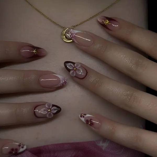 Mandelnägel in Nude und Bordeaux mit weissen 3D-Blüten und goldenen Sternen