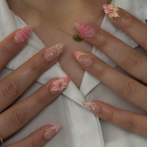 Mandelnägel in Zartrosa und Pastellgelb mit 3D-Muschelstruktur, Blüten und Perlen