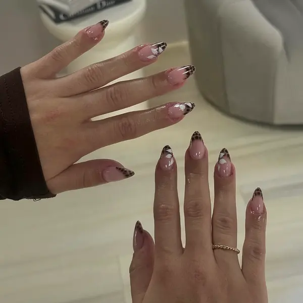 Mandelnägel in Zartrosa mit Leoparden-French-Tips und kleinen weissen Blüten